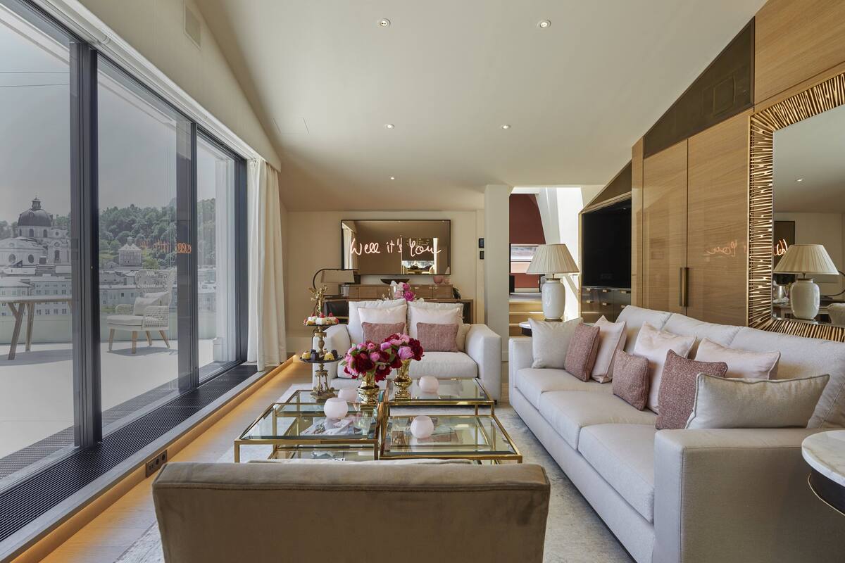 A modern living room with a large window, a white sofa, and a glass coffee table.