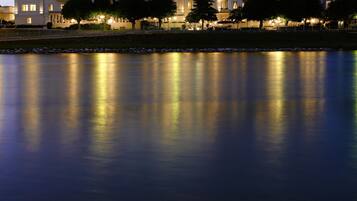A large hotel with multiple floors and balconies, situated by a calm body of water.