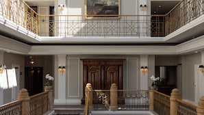 A multi-level interior with a central staircase, a glass ceiling, and a grand wooden door. - Hotel Sacher Salzburg (Salzburg)