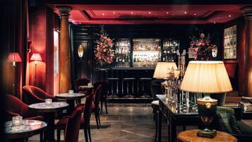 Eine Bar mit mehreren Tischen und Stühlen, einer Theke mit Flaschen und einer dekorativen Vase mit Blumen.