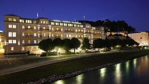 A large, multi-story hotel with balconies and a river in the foreground. - Hotel Sacher Salzburg (Salzburg)
