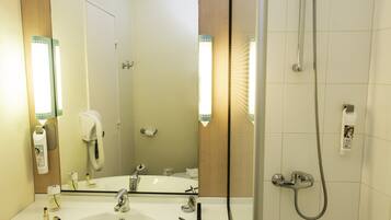 Un bagno con lavandino, specchio, portasciuga-asciugamani e doccia.