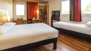 Habitación de hotel con dos camas, un escritorio, un televisor y una ventana con cortinas.