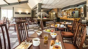 Un comedor de hotel con varias mesas, sillas y una cocina al fondo.