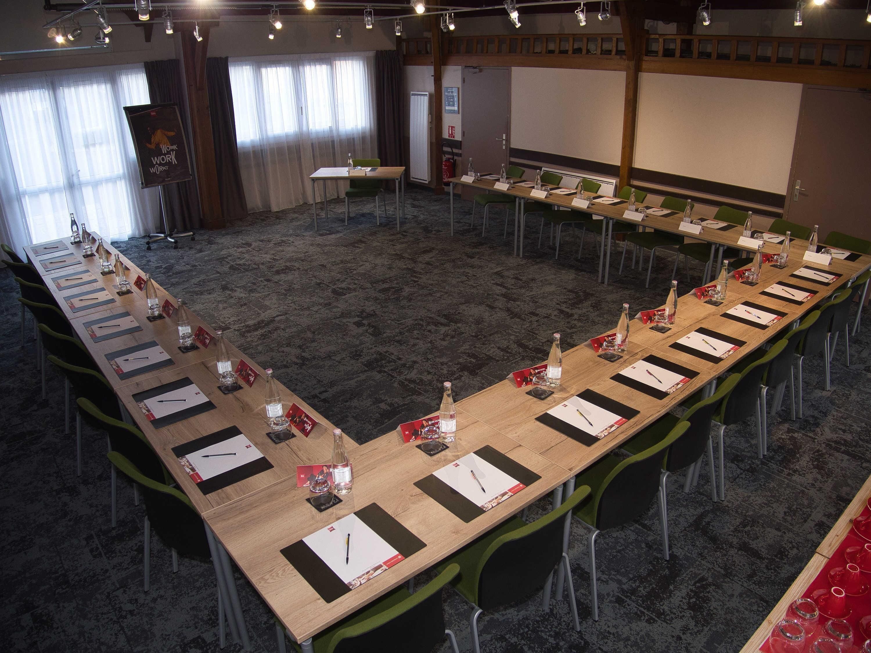 A conference room with long tables, chairs, nameplates, and water bottles.