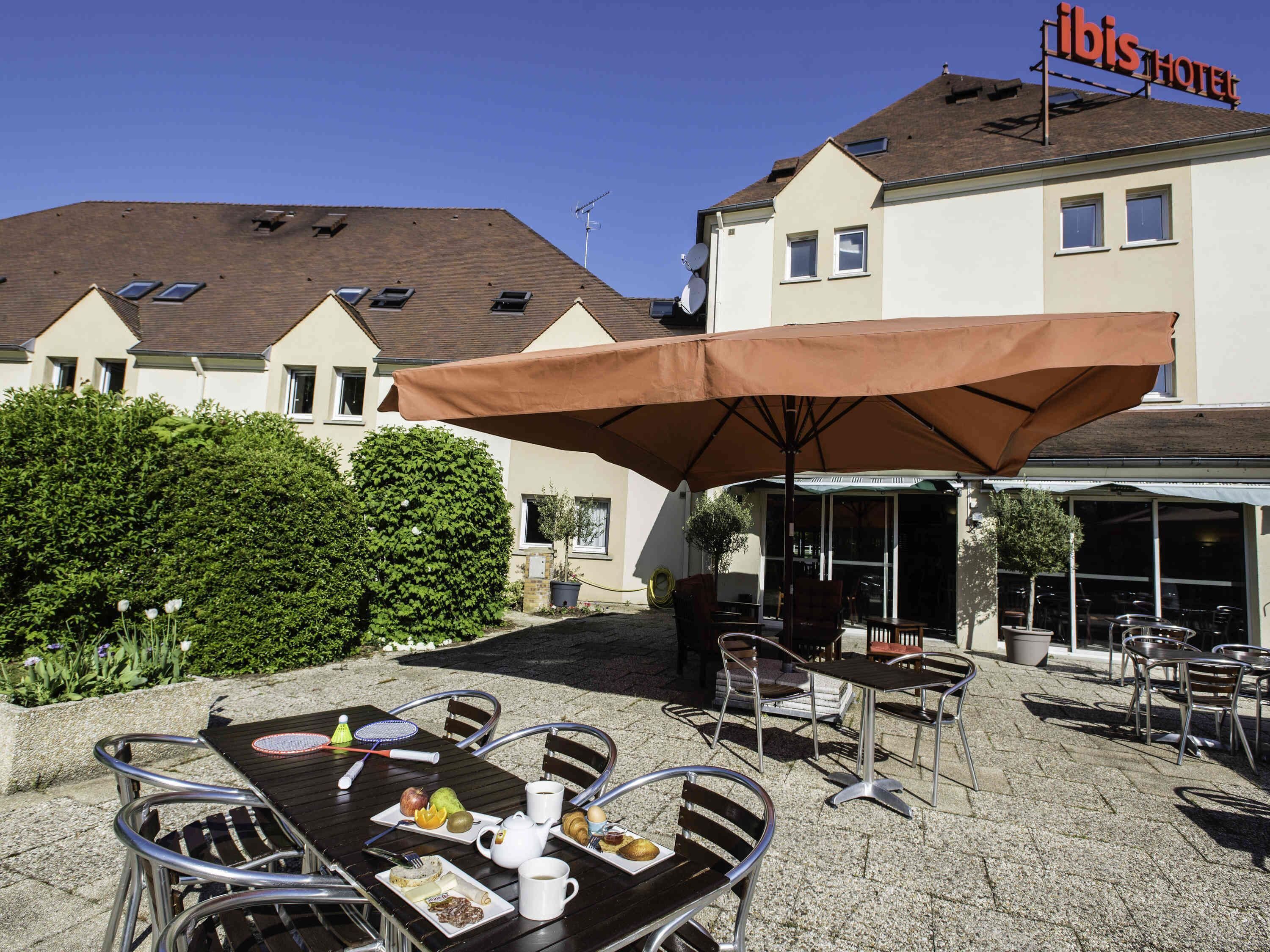 An outdoor seating area with tables, chairs, and umbrellas at a hotel.