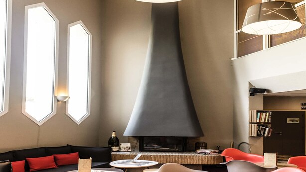 Un área de estar moderna con sofá, sillas, mesas, chimenea y estantería.
