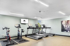 A gym with treadmills, stationary bikes, and a wall-mounted screen displaying the logo "DupleTree by Hilton".