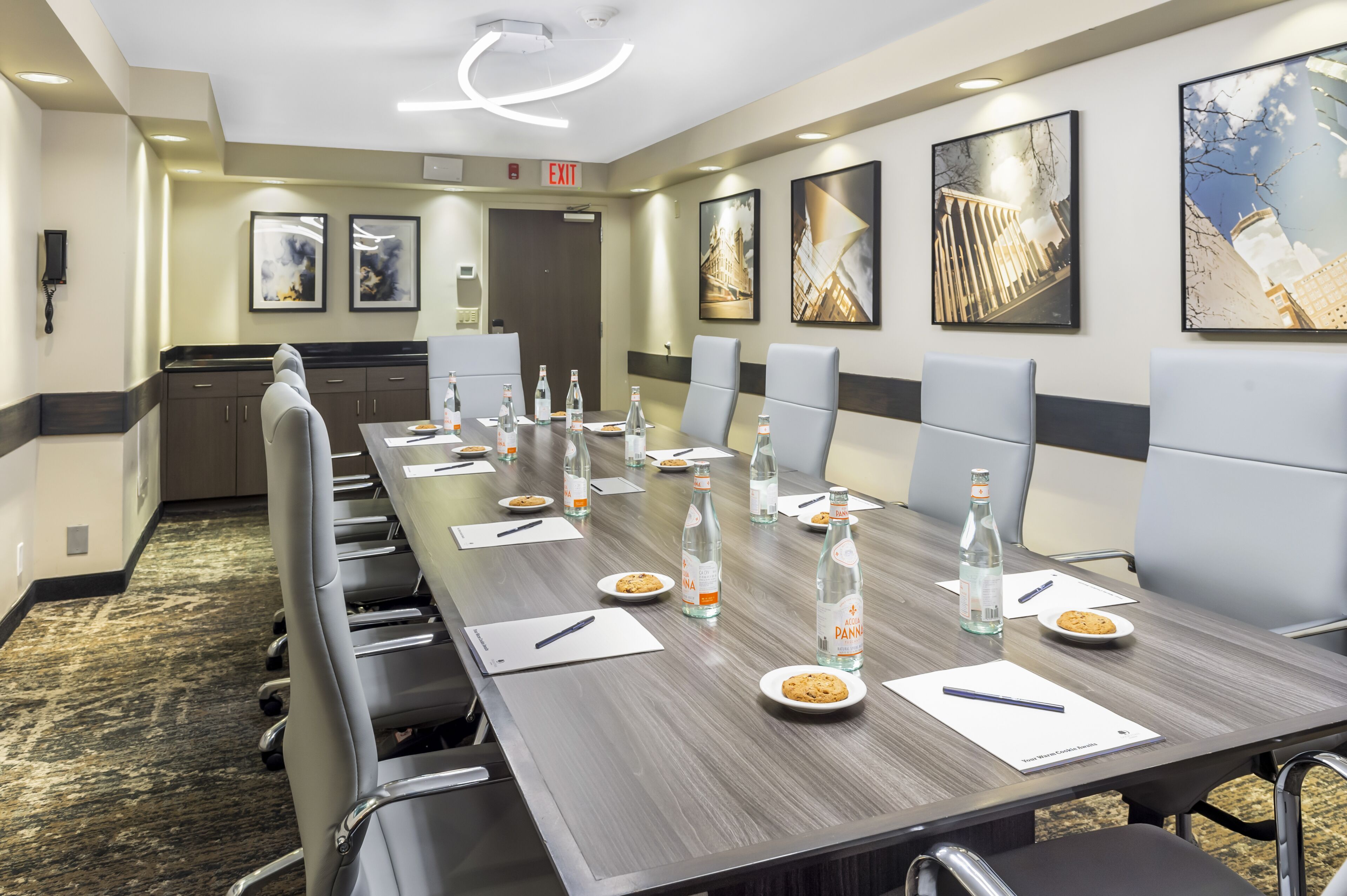 A conference room with a long table, chairs, water bottles, plates with cookies, and a whiteboard.