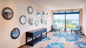 A lobby with a large window, a bench, and multiple wall-mounted mirrors. - Hilton Garden Inn Providence (Providence)