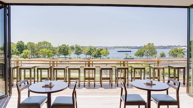 A terrace with tables and chairs overlooking a river. - Hilton Garden Inn Providence (Providence)