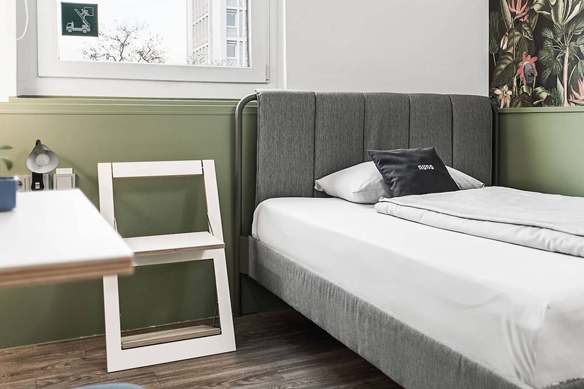 A neatly arranged bedroom with a bed, a bedside table, and a chair.