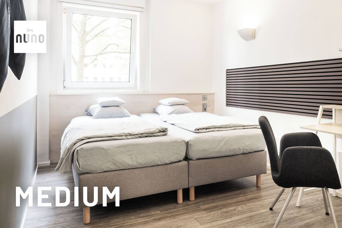 A medium-sized room with a bed, a desk, and a chair.