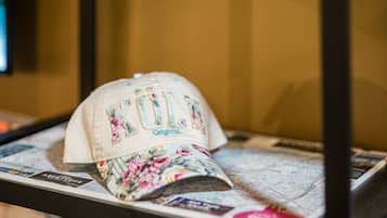 A cap with embroidered text and floral design on a display stand.