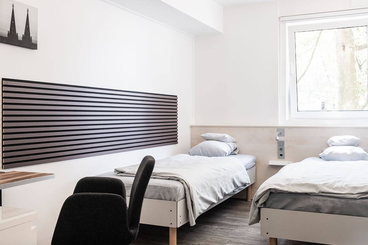 A bedroom with two beds, a desk, and a chair.