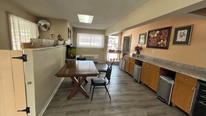 Une cuisine compacte avec une table et des chaises en bois, un four encastré et un petit réfrigérateur.