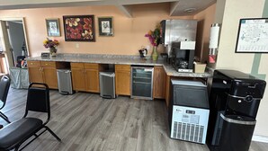Une cuisine compacte avec des meubles en bois, un lave-vaisselle encastré, une machine à café et un réfrigérateur.