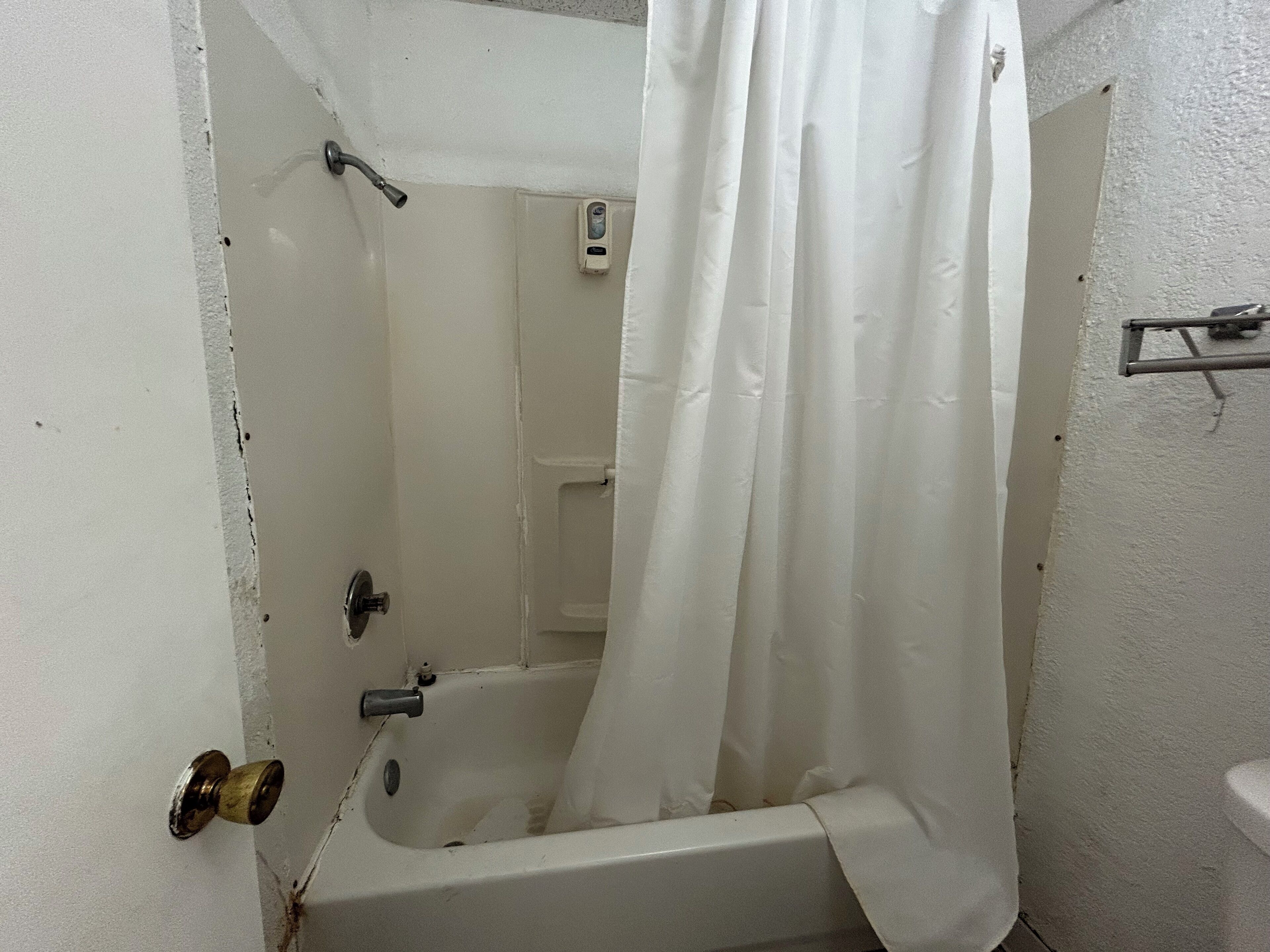 Une salle de bain avec une baignoire, un rideau de douche et un sèche-mains.