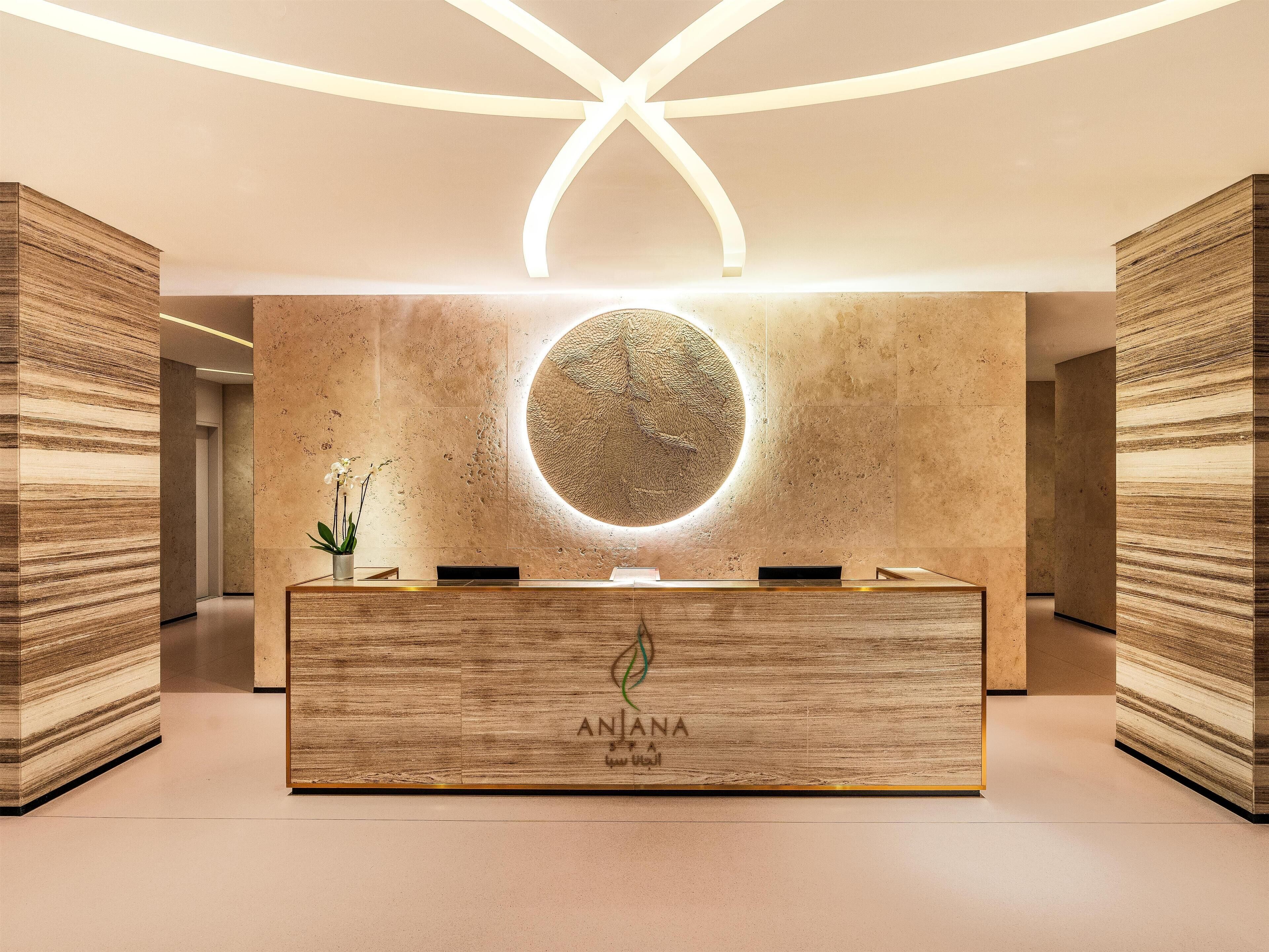 Un comptoir d’accueil surmonté d’un luminaire circulaire, et flanqué de panneaux en bois.