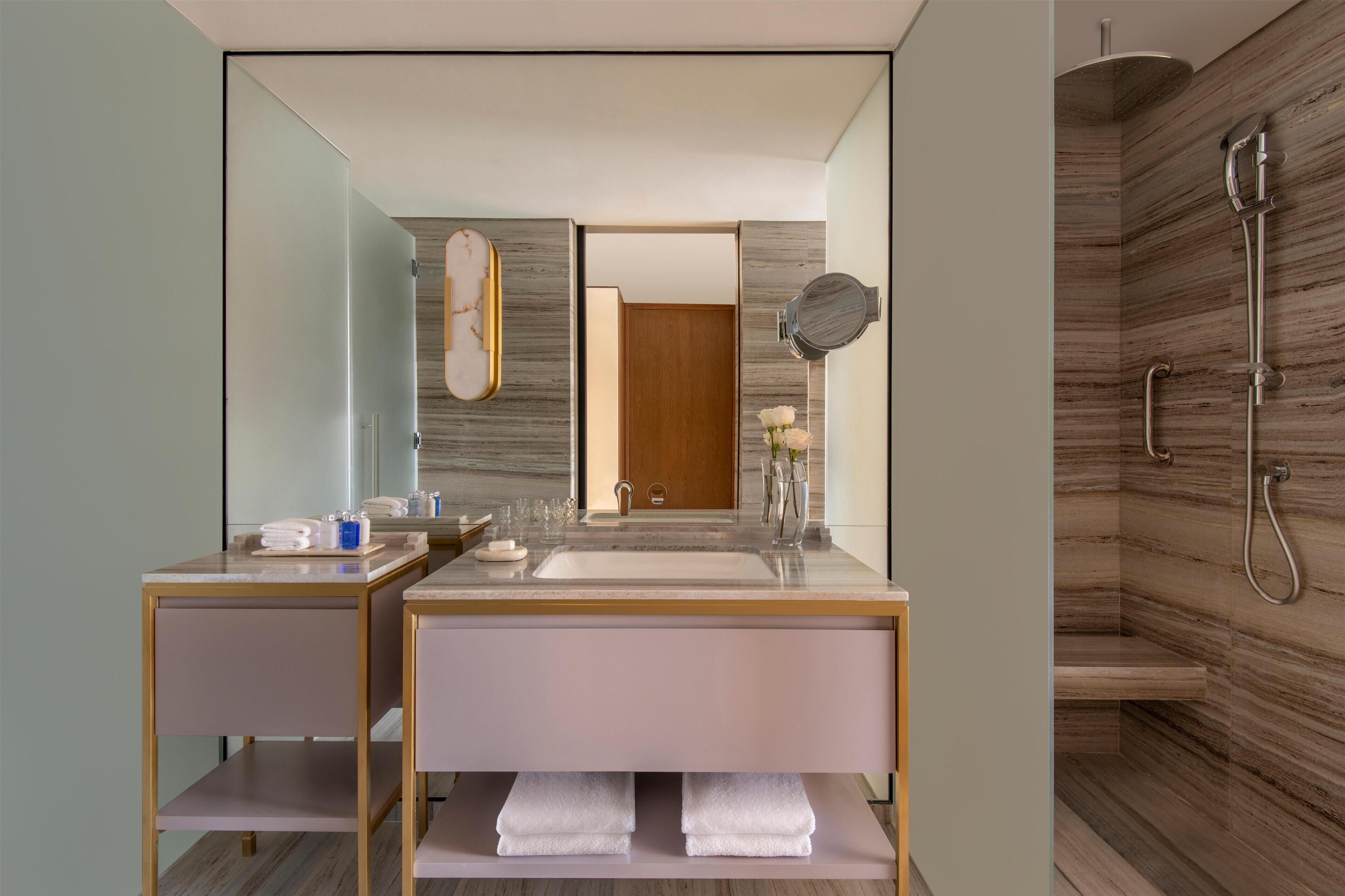 Een moderne badkamer met twee wasbakken, een grote spiegel en een douche.