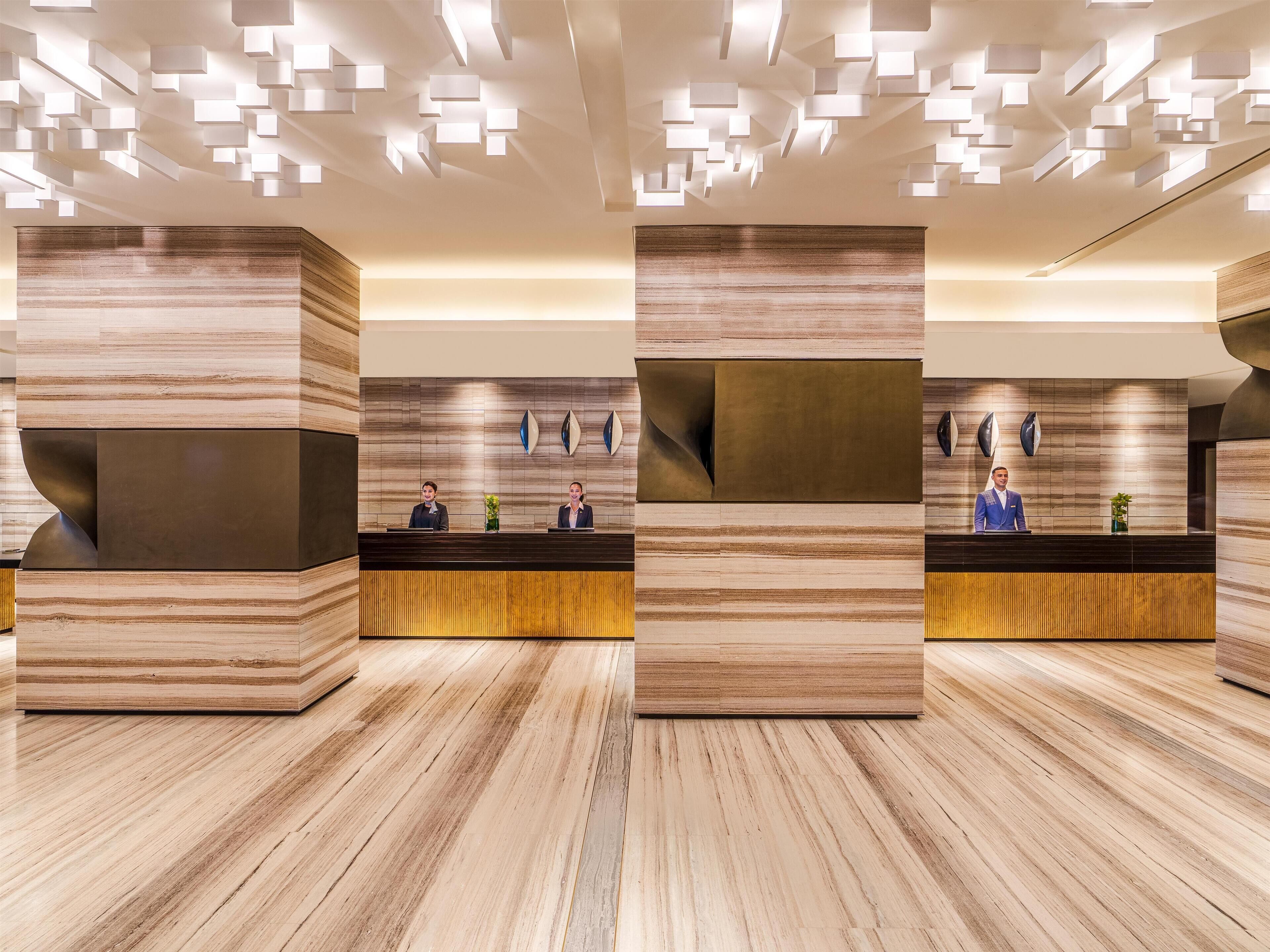 Un área de recepción moderna con un panel de madera, un mostrador de recepción y una lámpara de techo original.