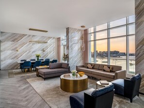 A modern living room with a dining area, large windows with a city view, and marble walls.