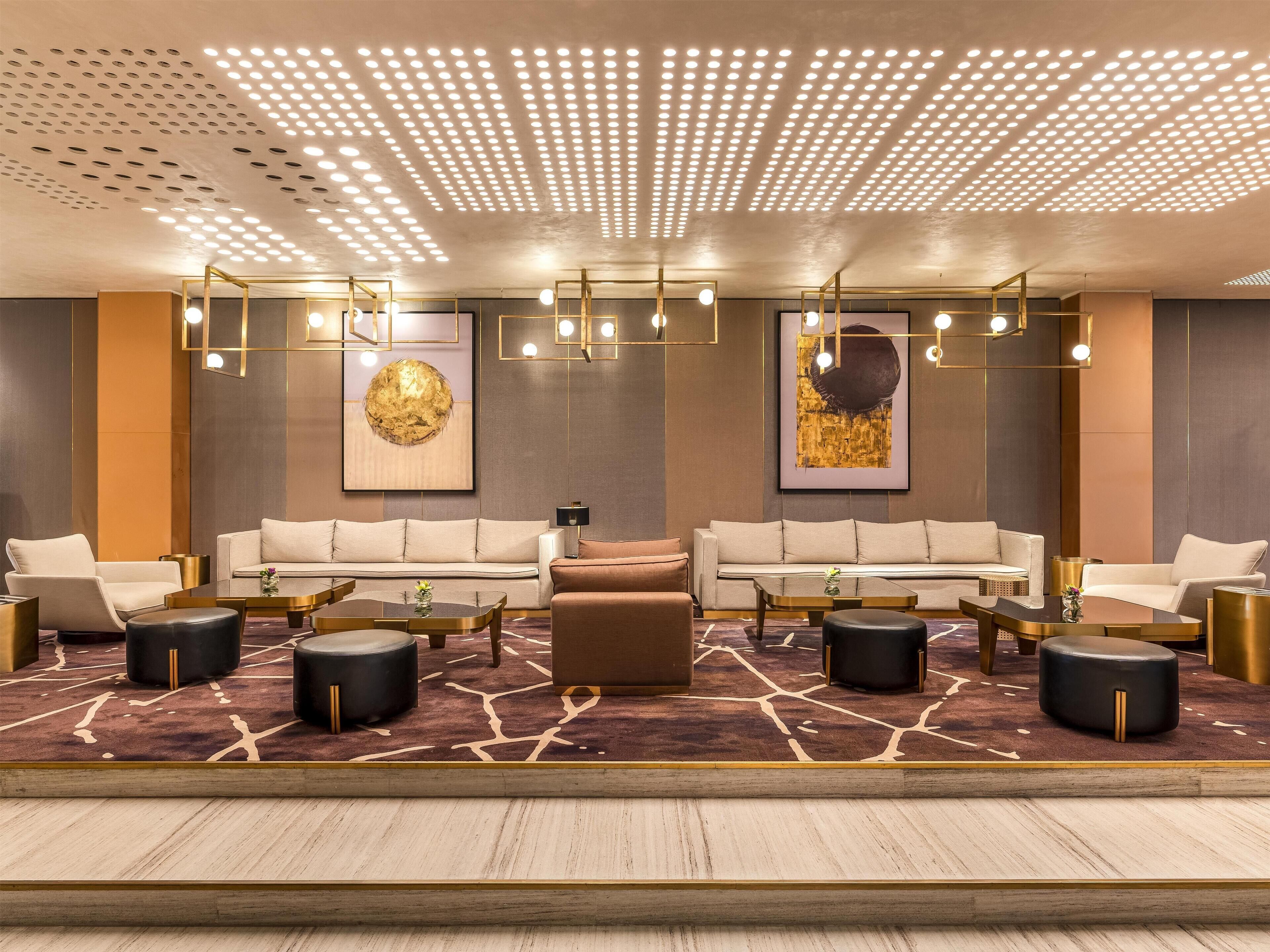 A modern lounge area with sofas, tables, and a patterned carpet.