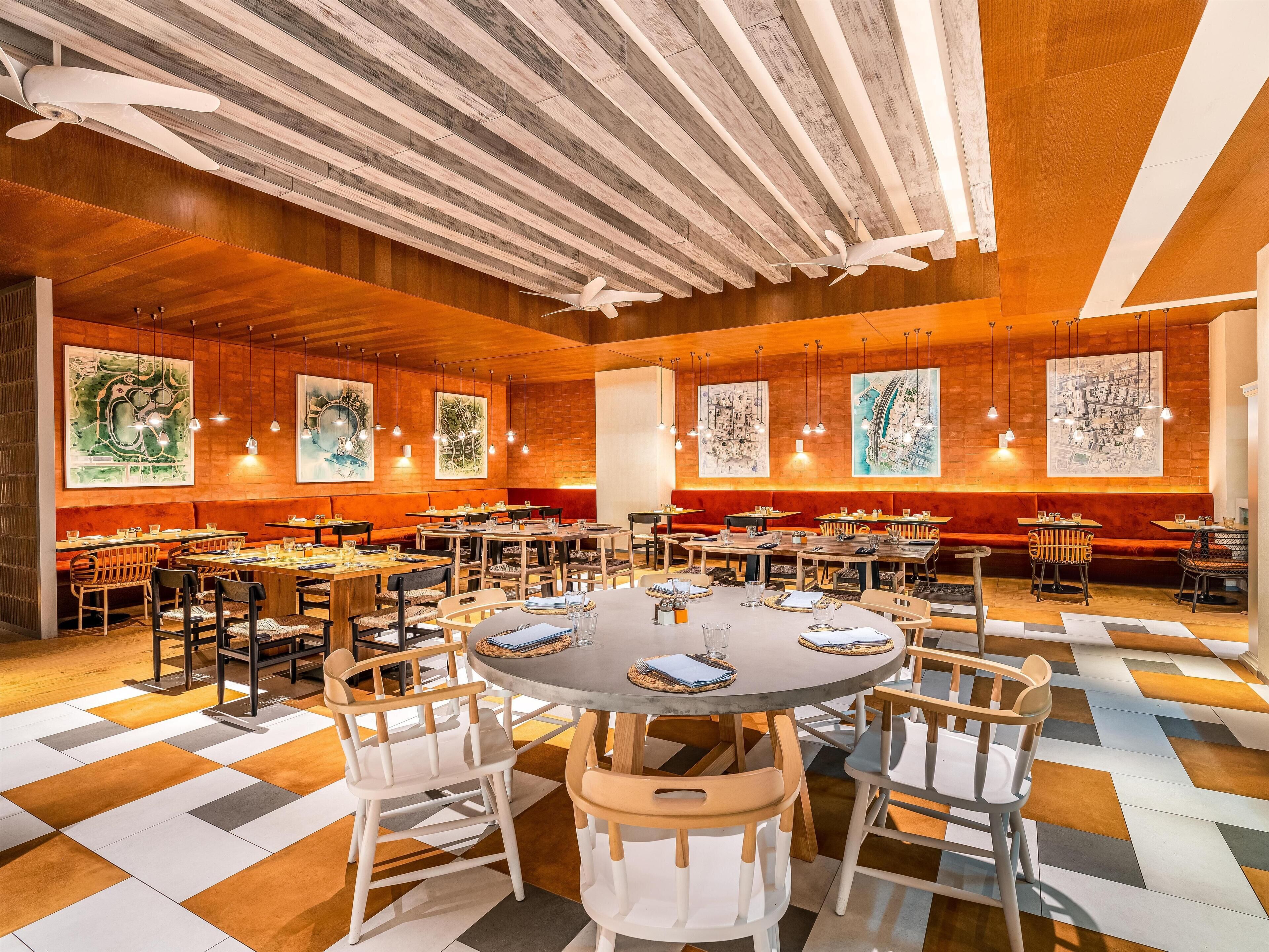Ein geräumiges Restaurant mit hohen Decken, Holzbalken und einer Mischung aus runden und rechteckigen Tischen.