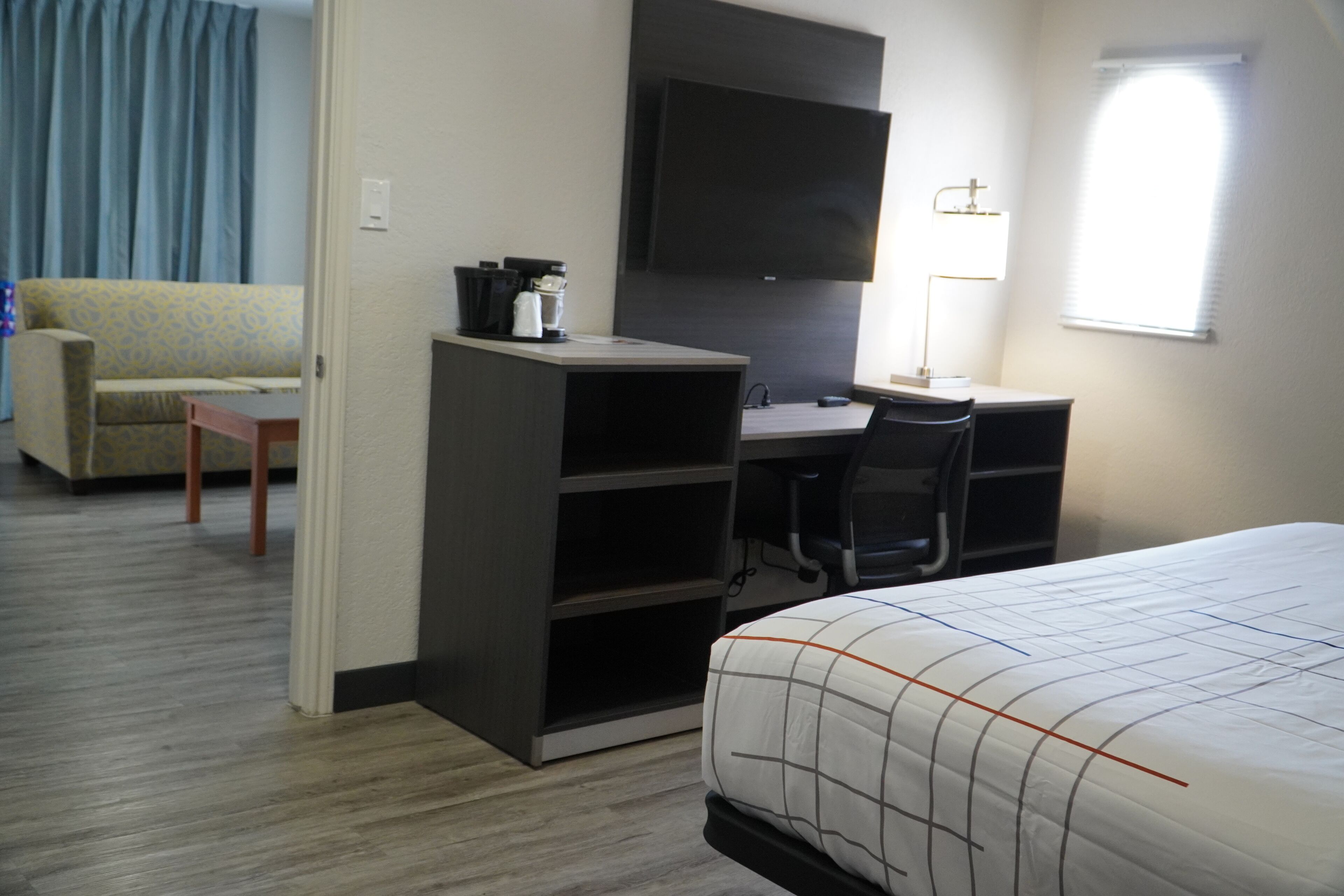 Une chambre d’hôtel équipée d’un lit, d’un bureau, d’une chaise, d’une télévision, d’une machine à café et d’un canapé.