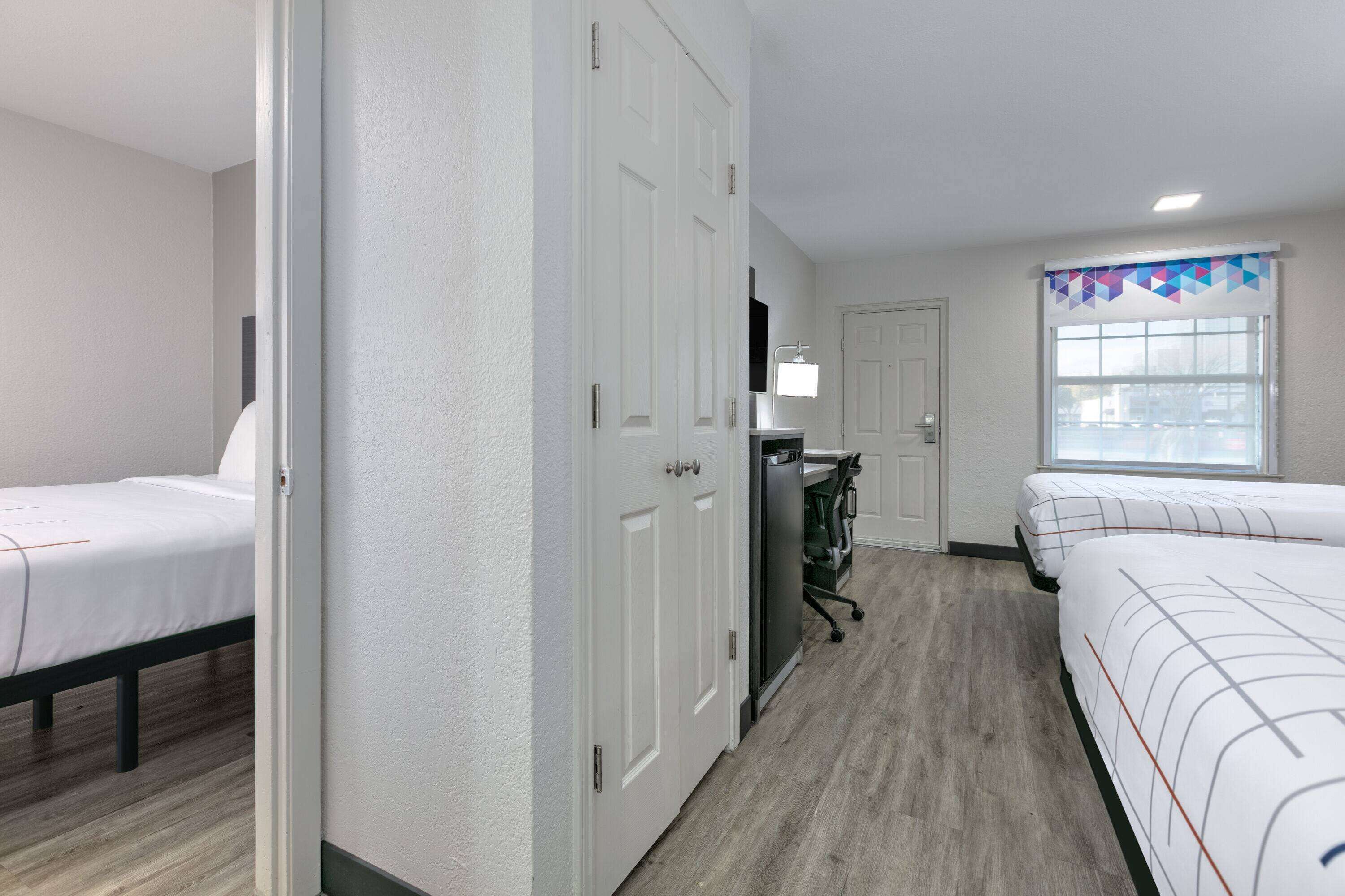 A hotel room with two beds, a desk, and a wardrobe.