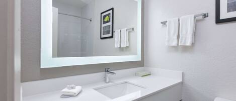 Een moderne badkamer met een grote spiegel, een witte wastafel en een toilet.