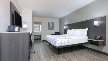 Une chambre d’hôtel moderne dotée d’un grand lit, d’un bureau, d’une télévision à écran plat et d’une petite table de chevet avec un téléphone.