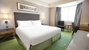 A hotel room with a large bed, a desk, a chair, and a small table.