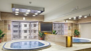 A hotel lobby with a reception desk, two hot tubs, and a large mirror. - Holiday Inn Macau by IHG (Macau)
