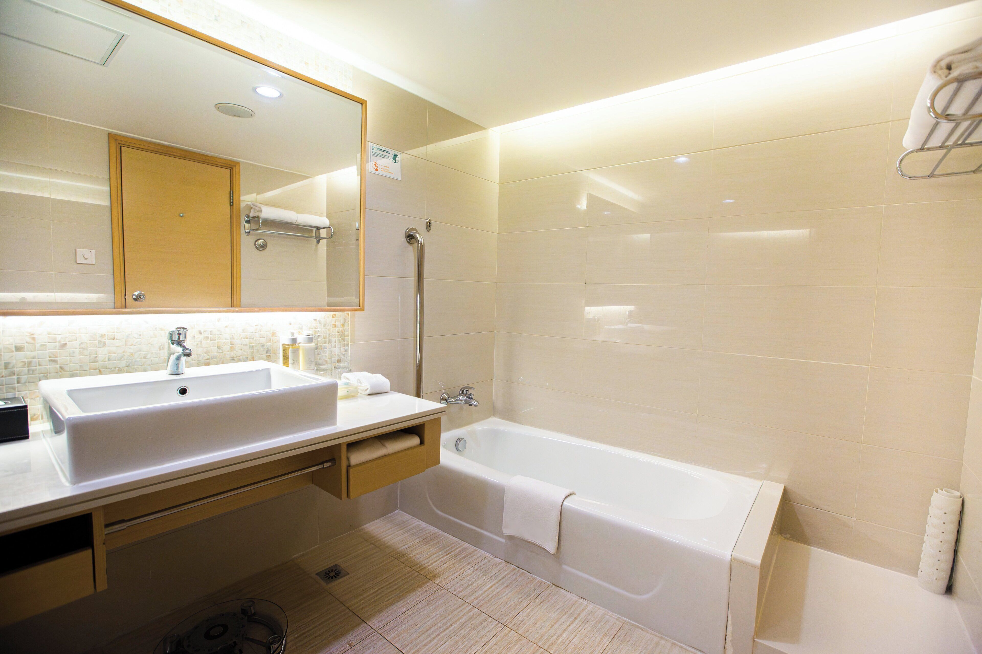 Un baño moderno con un lavamanos grande, una bañera y un espejo.