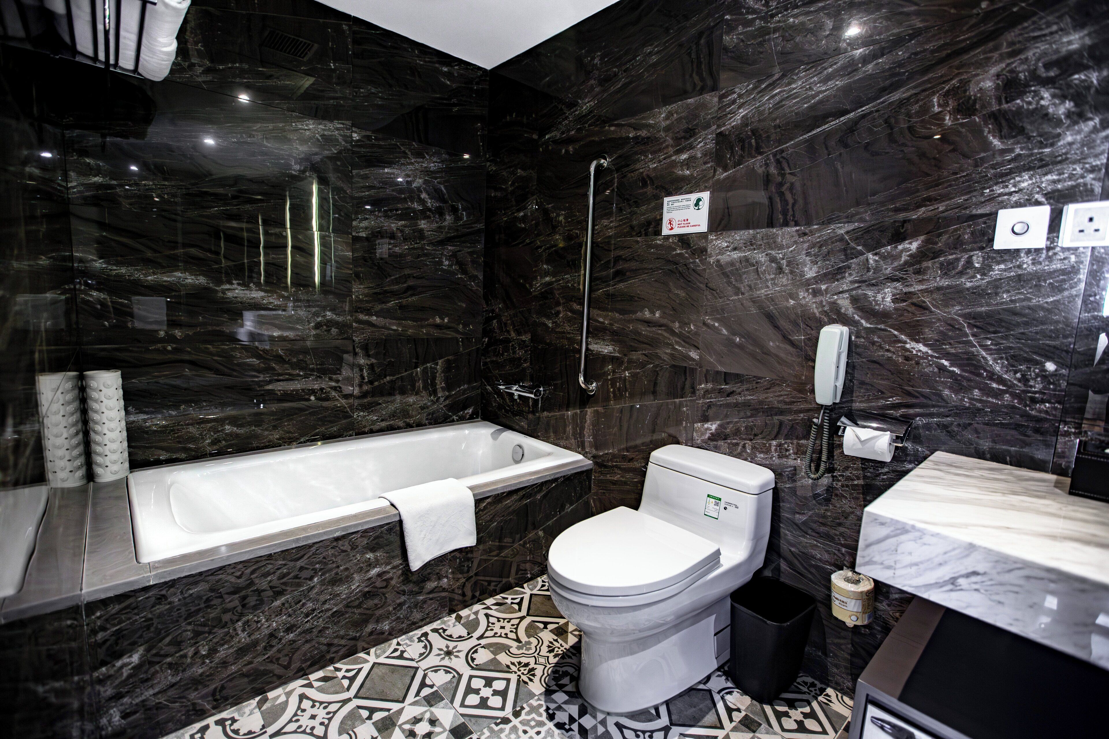 A modern bathroom with a marble floor, a bathtub, a toilet, and a sink.