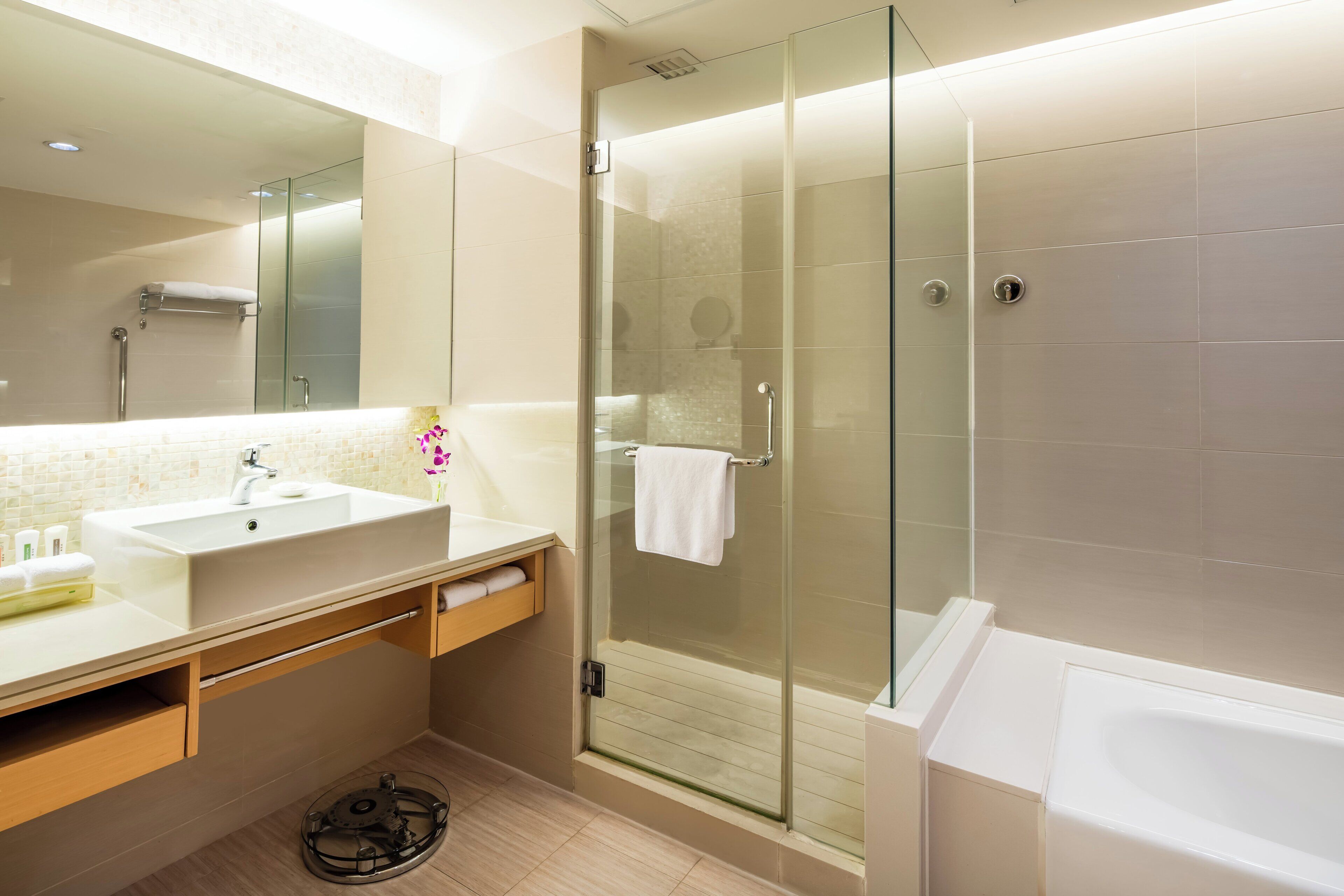 Un baño moderno con ducha envuelta en vidrio, lavamanos blanco y bañera.