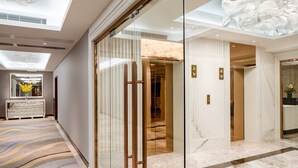 A modern hotel lobby with a marble floor, a reception desk, and a glass elevator. - Holiday Inn Macau by IHG (Macau)