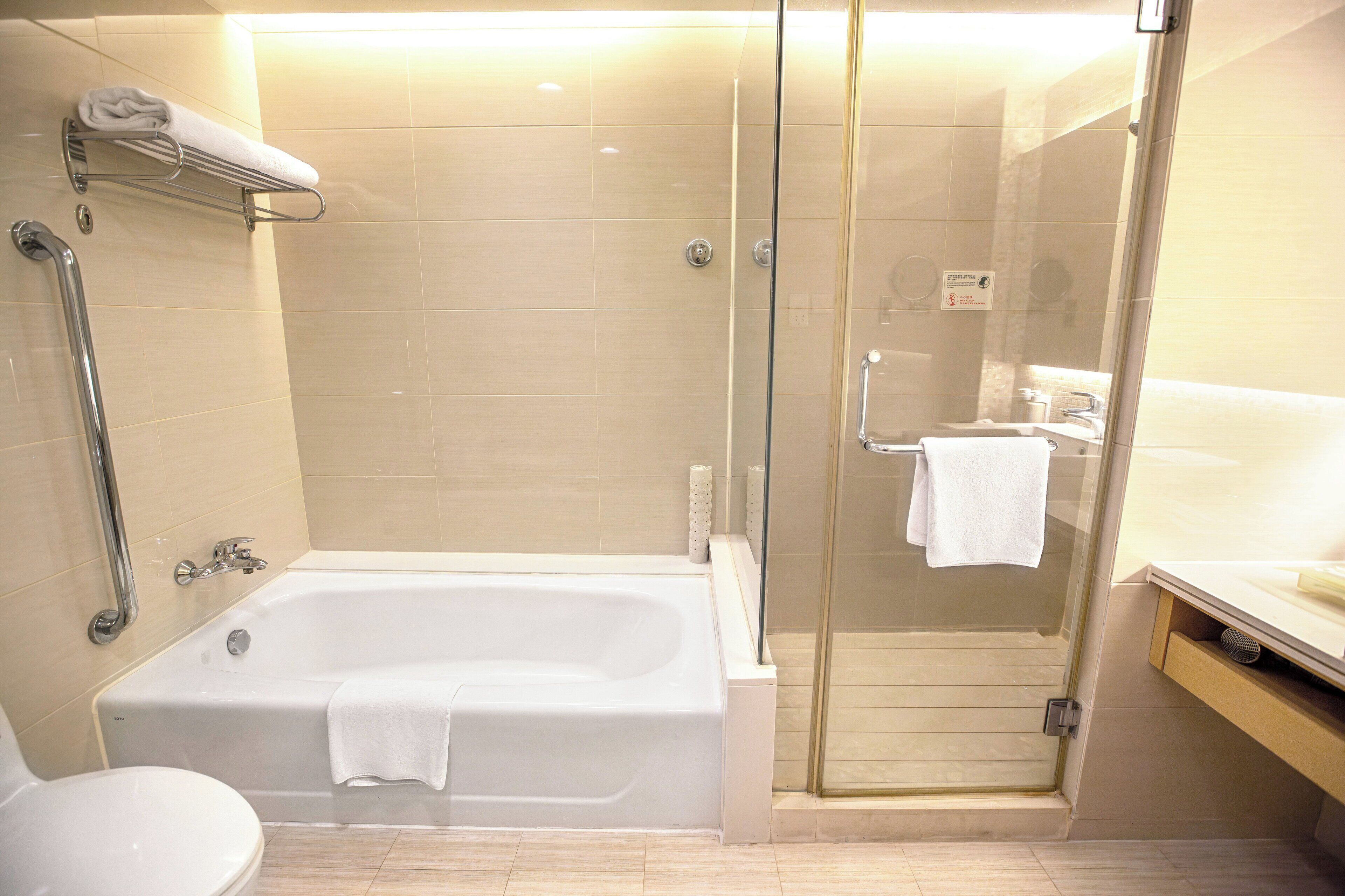 A modern bathroom with a glass-enclosed shower, a bathtub, and a toilet.