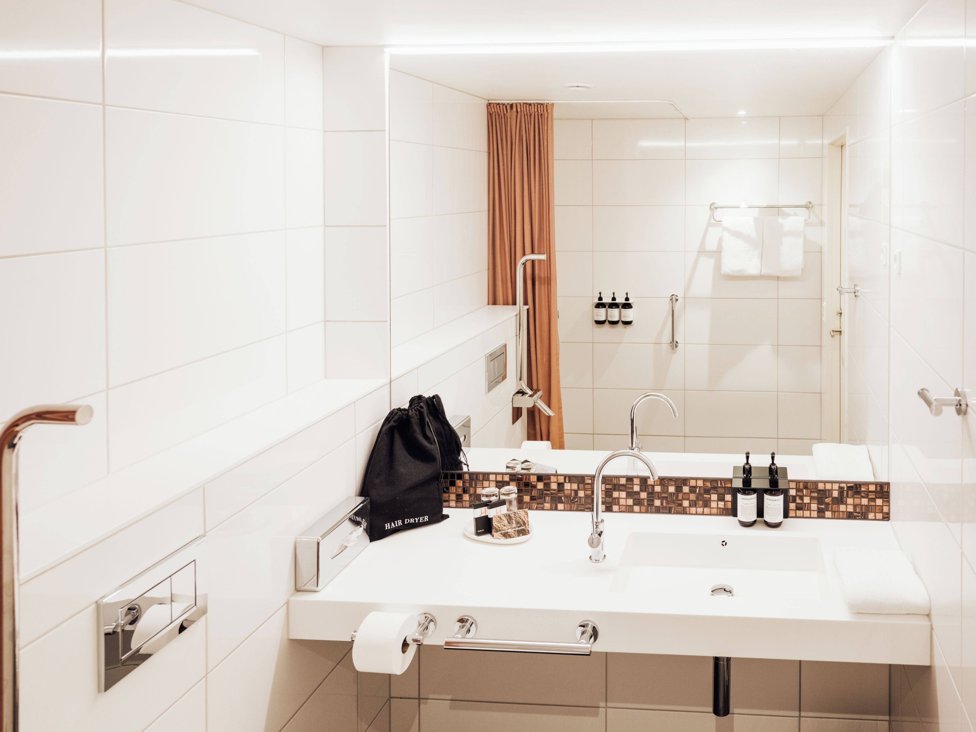 Une salle de bain moderne avec un lavabo blanc, un miroir et un porte-serviettes.