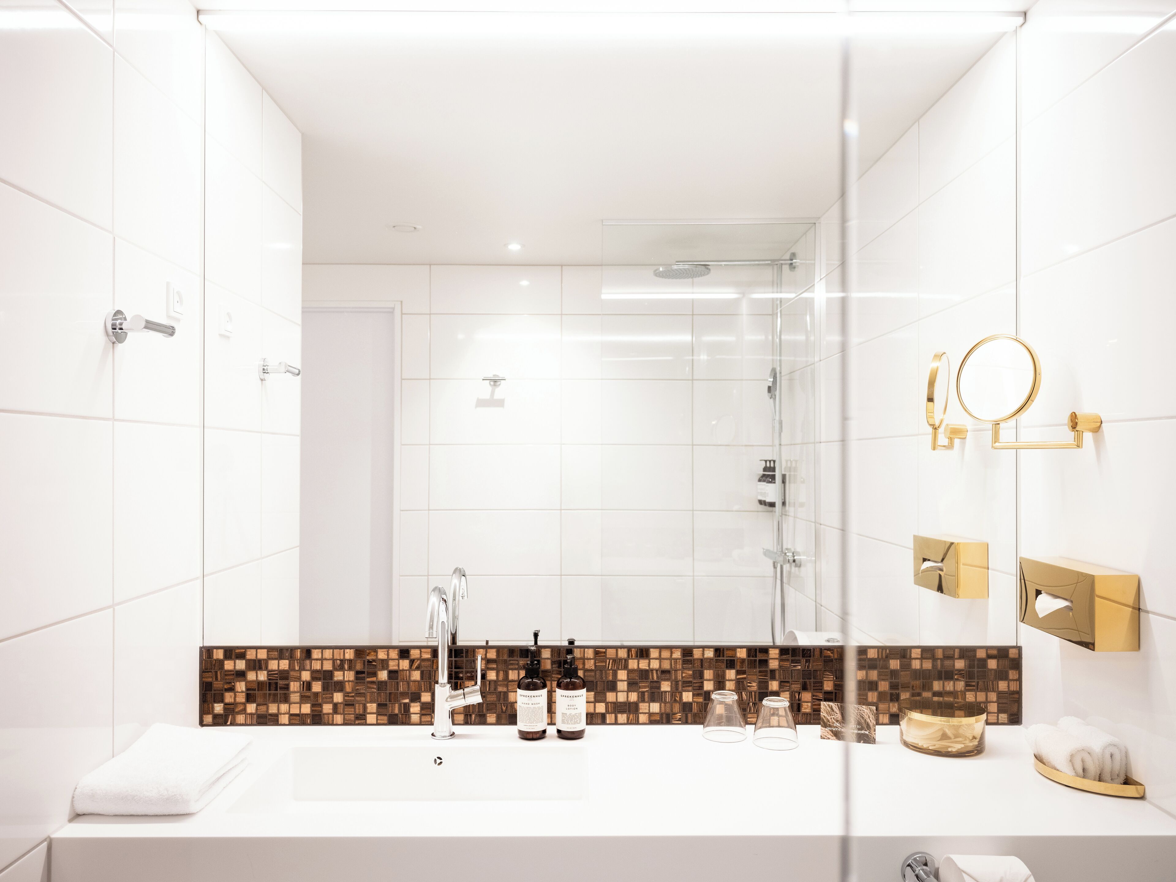 Un baño moderno con un espejo grande, ducha y tocador con lavabo blanco.