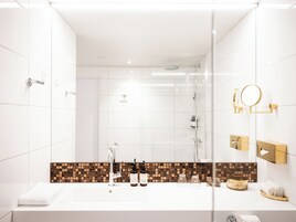 Un baño moderno con un espejo grande, ducha y tocador con lavabo blanco.