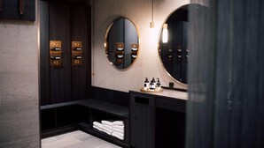 A modern bathroom with a vanity, a bench, and a towel rack. - Hotel Føroyar (Tórshavn)
