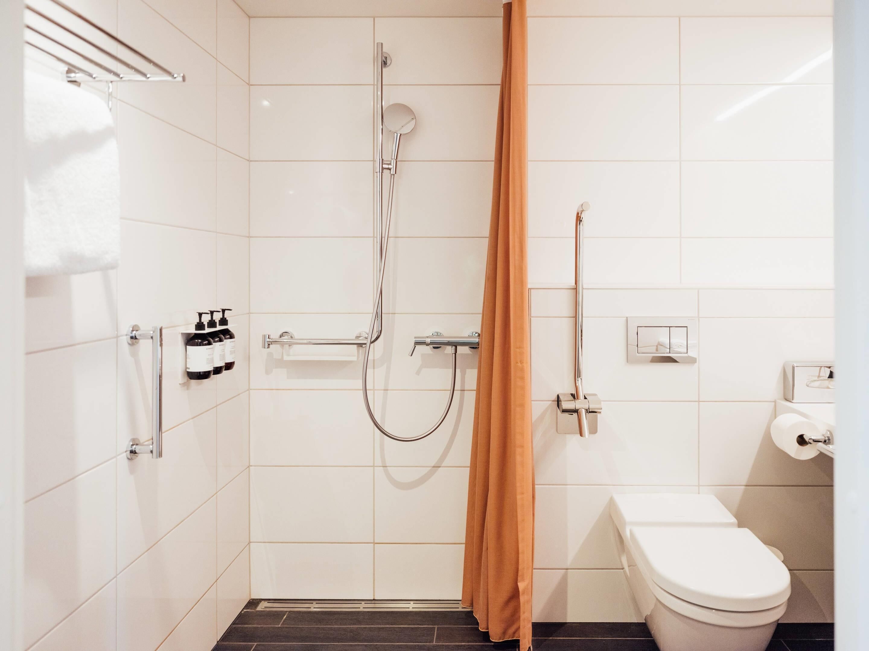 Ein modernes Badezimmer mit Dusche, Toilette und Handtuchhalter.