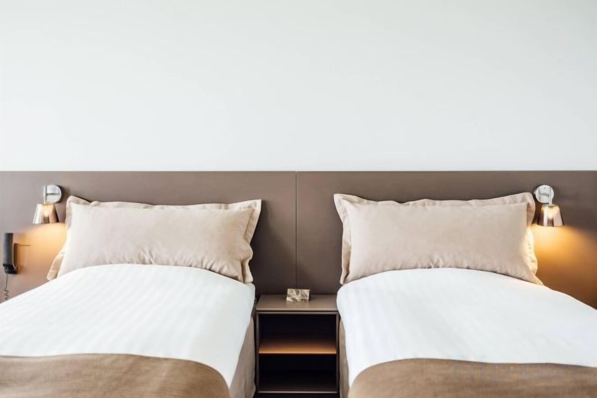 A double bed with a headboard, bedside tables with lamps, and a small shelf.