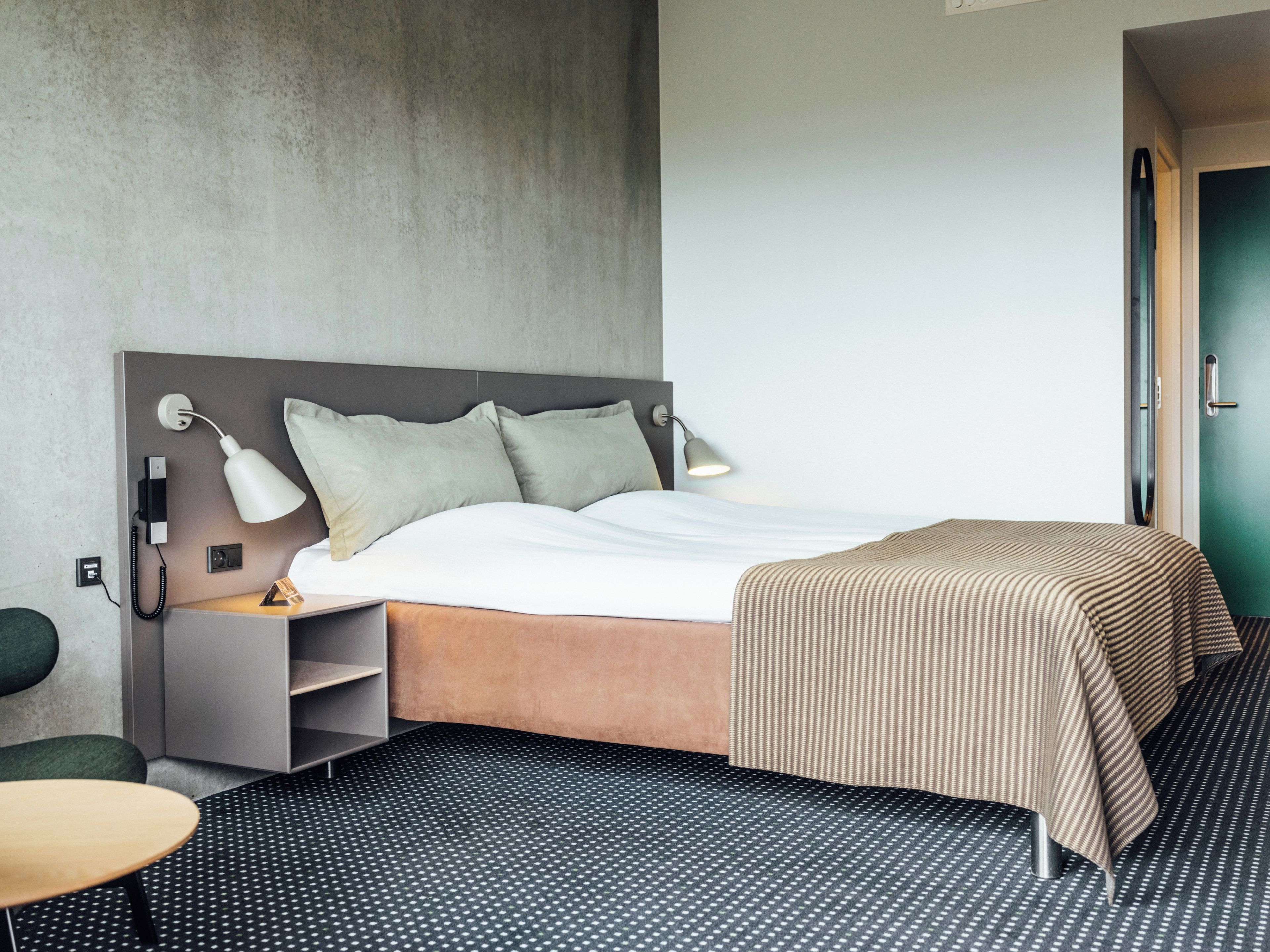 Et hotelværelse med seng, sengeborde, skrivebord og stol.