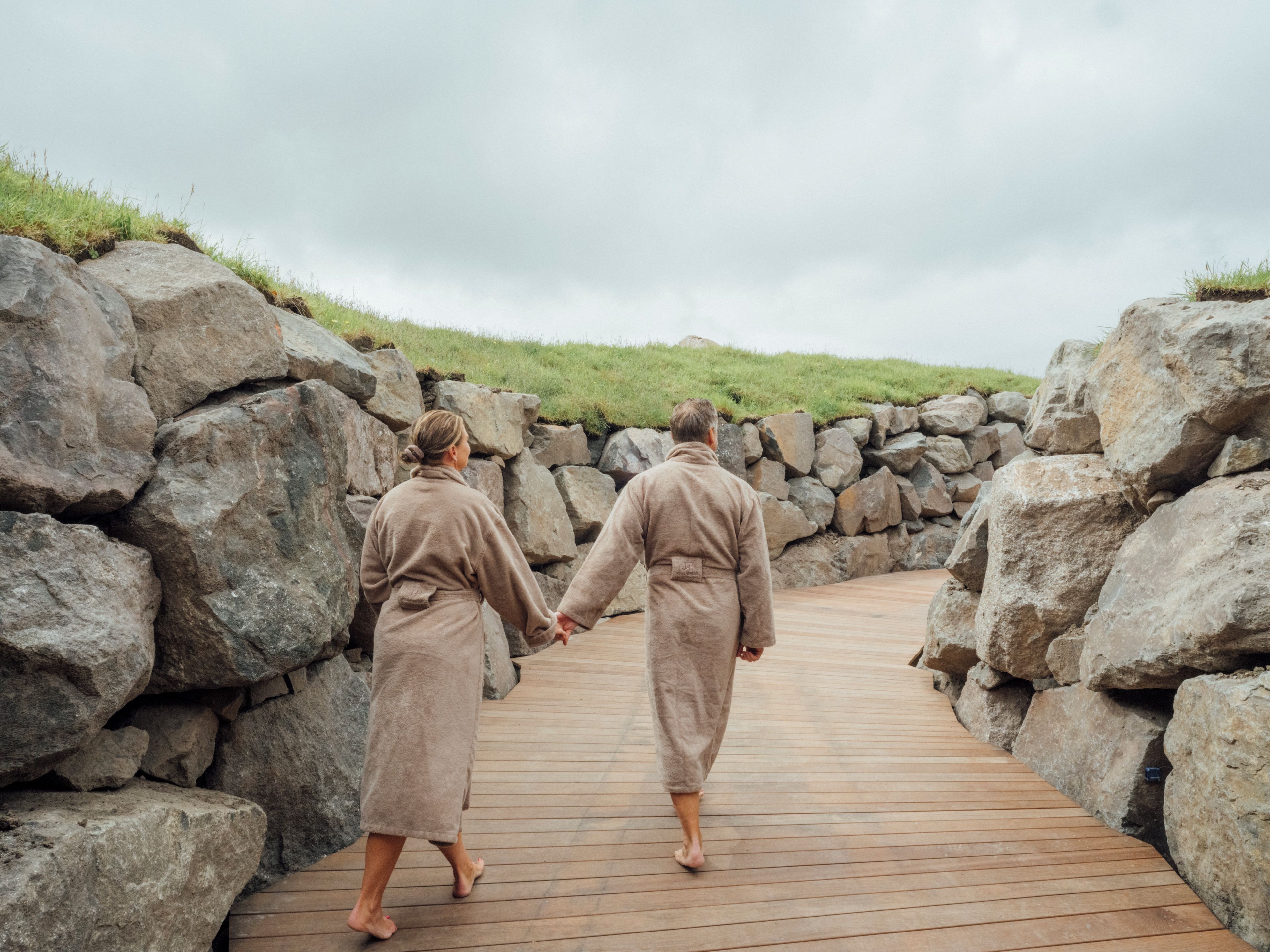 A wooden pathway flanked by large rocks, leading to a grassy area.