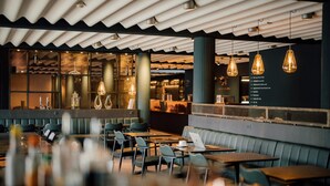 A modern restaurant with a high ceiling, pendant lighting, and a mix of seating options including tables and booths. - Hotel Føroyar (Tórshavn)