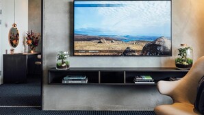 A modern living room with a large landscape painting, a sofa, a coffee table, and a bookshelf. - Hotel Føroyar (Tórshavn)