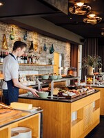 A buffet setup with various food items and a bartender preparing drinks.